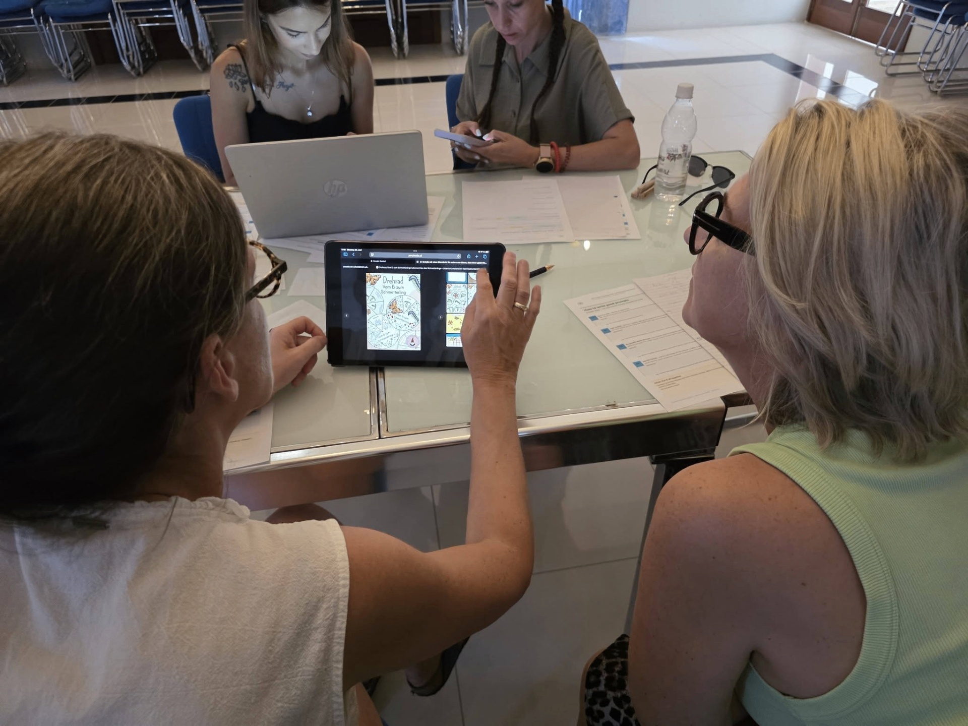 Teachers collaborating around a tablet during a digital tools workshop in Gozo