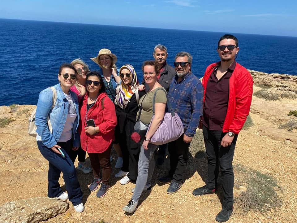 Group of teachers posing on a Gozo cliffside above the sea during a study visit