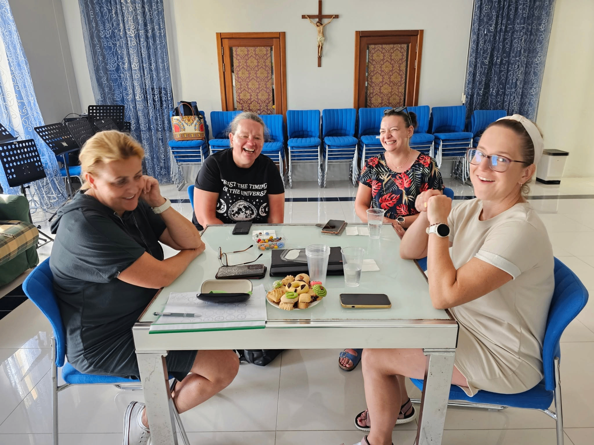 International teachers laughing around a meeting table during a training break in Gozo